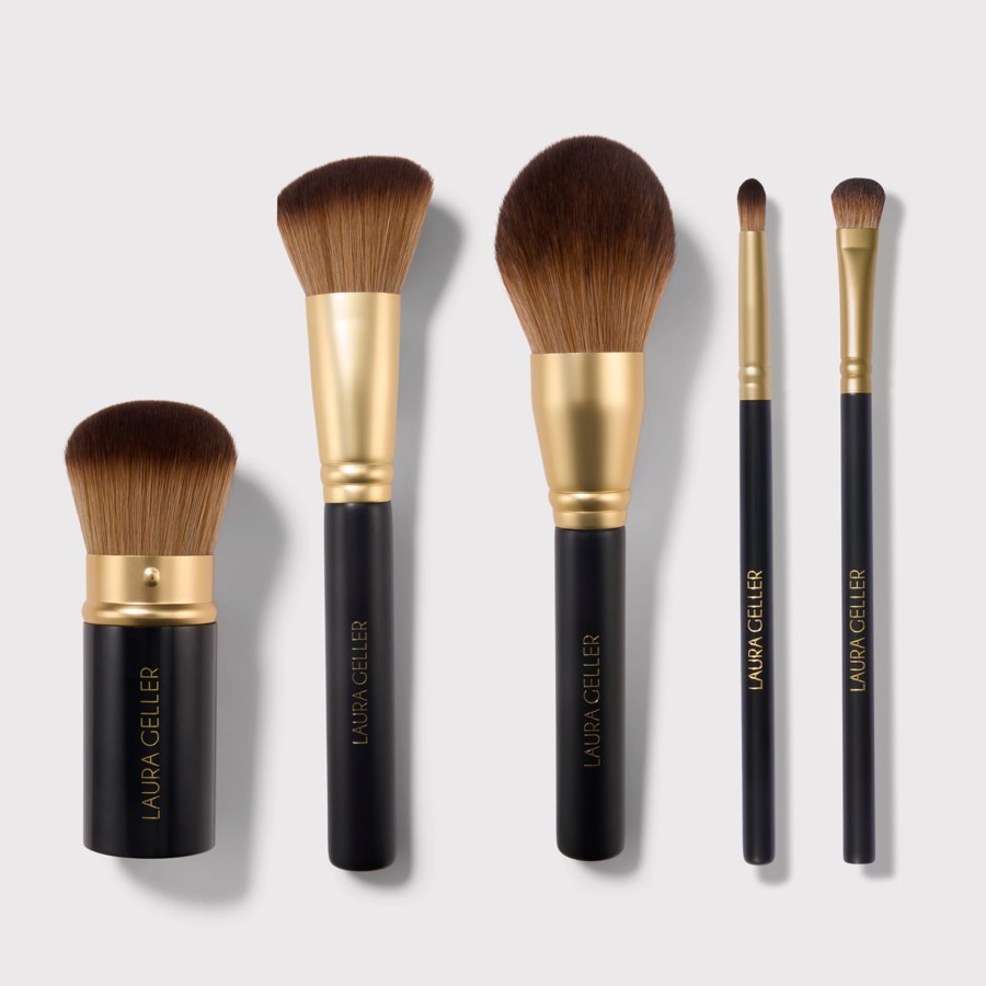 The five Laura Geller brushes side by side: retractable kabuki, angled blush, face and body, all-over eyeshadow and blending crease, black handles with gold ferrules